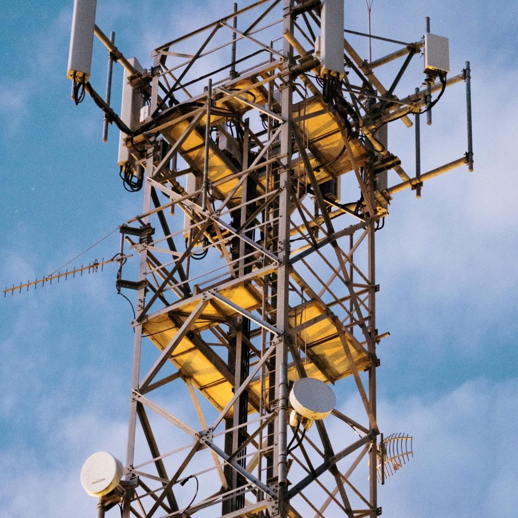 Close-up of a modern telecommunications tower with antennas set against a clear blue sky.