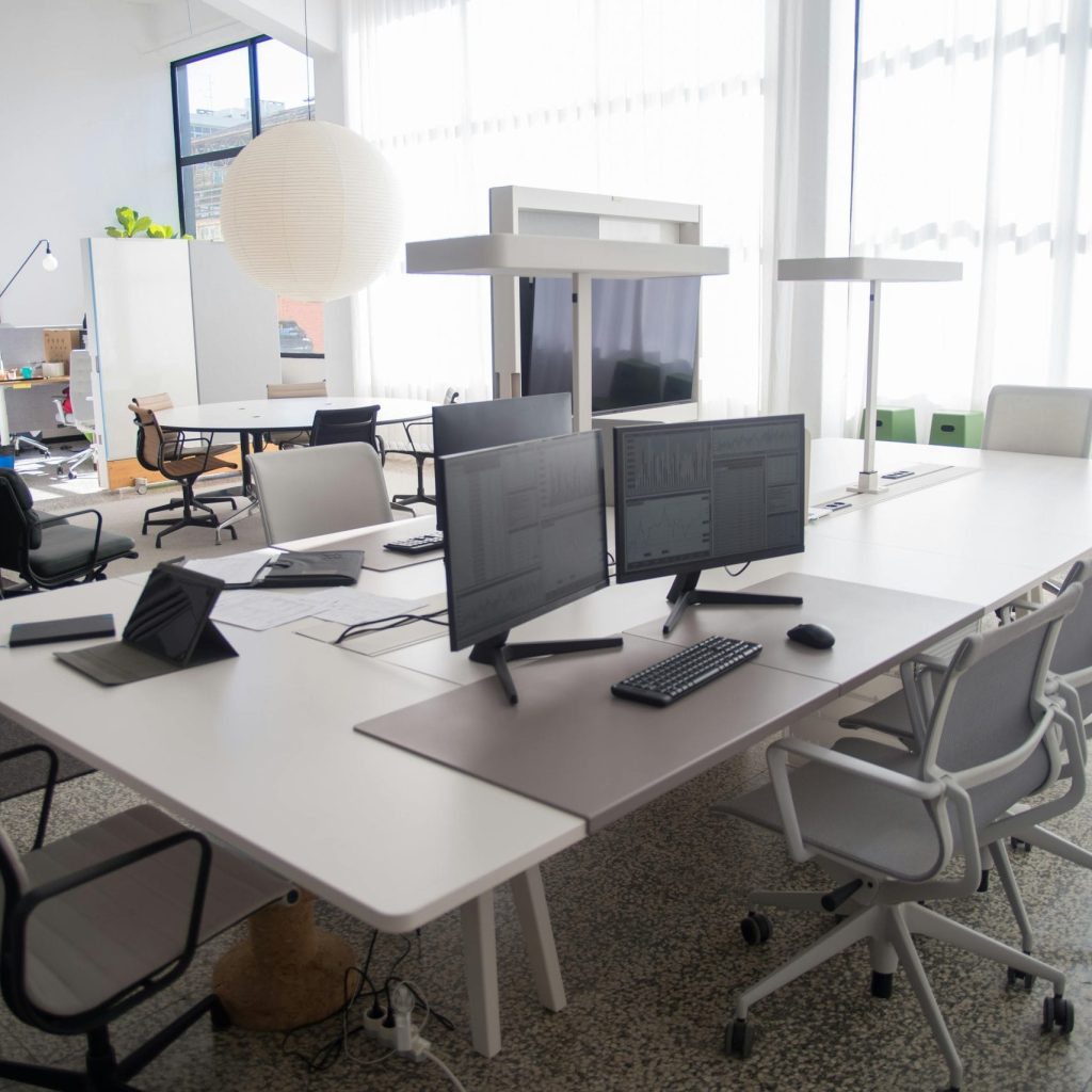 Spacious and organized open office workspace with modern furniture and natural lighting.